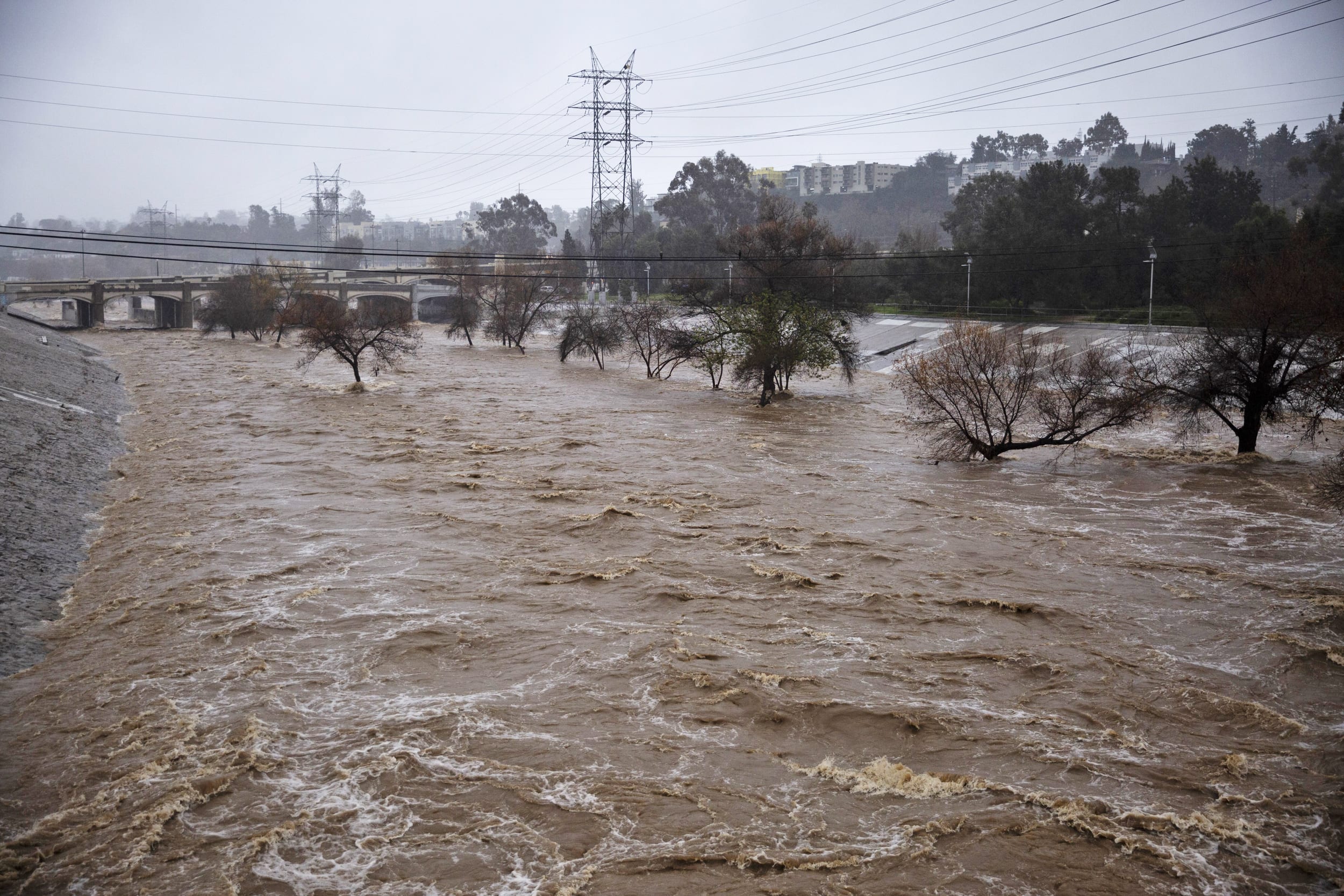 A swollen river in flood under transmission lines